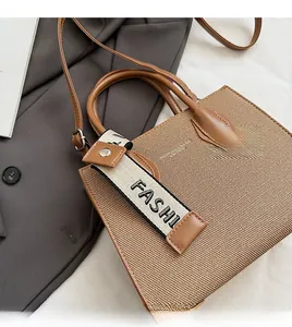 Détail d'un sac cabas tissé avec garniture en similicuir marron et bandoulière amovible