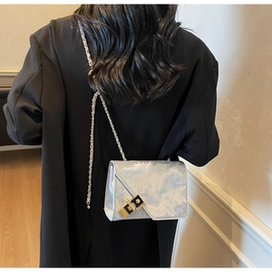 Detail of silver textured chain bag featuring a signature black and gold square lock closure