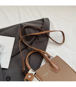 Sac à main tissé marron avec foulard en soie posé sur un blazer gris au style chic