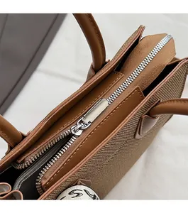 Détail de la fermeture éclair argentée sur sac en cuir marron avec poignée en foulard
