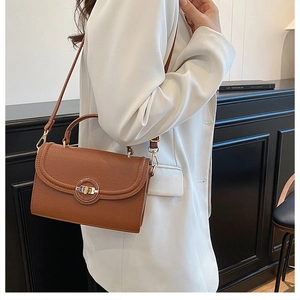 Detailed view of a brown pebbled leather crossbody bag with a gold metal rotary lock buckle