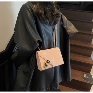 Model wearing a pink patent leather chain crossbody bag with black gold lock detail