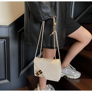 Close-up of beige leather crossbody bag with gold square buckle and chain strap detailing