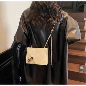 White glossy patent leather crossbody bag featuring gold chain strap and metal lock detail