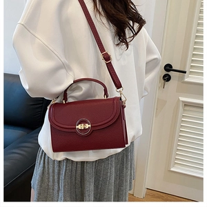 Detail of burgundy crossbody bag with lychee grain leather and gold metal ring buckle