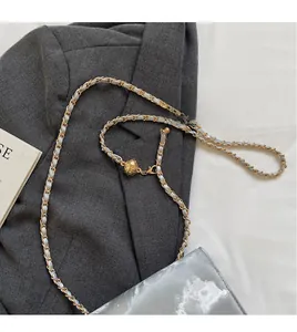 Detail of adjustable gold metal chain strap with woven fabric for crossbody bag