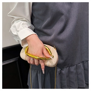 Close-up of woven straw box bag featuring a unique gold metal handle and chain strap