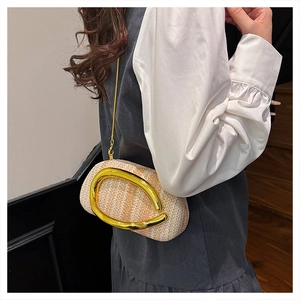 Close-up of woven straw evening bag featuring a large gold C-shaped metal buckle detail