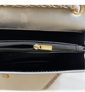 Detail of silver metallic crossbody bag showing smooth golden zipper and black lining