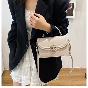 Detail of beige textured crossbody bag with gold round metal twist lock and model styling