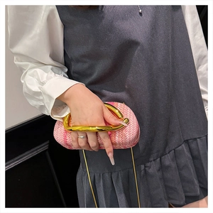 Detail of pink woven clutch with a distinctive curved gold metal handle and chain strap
