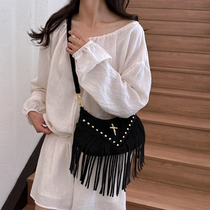 Crossbody bag with black fringe, gold rivets, and a cross pendant in suede material