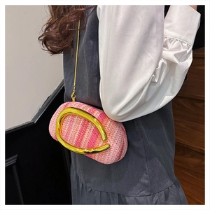 Detail of colorful woven shoulder bag with gold C-shaped buckle on a model
