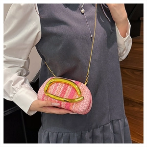Detail of pink woven wristlet bag with gold U-handle and delicate metal chain strap