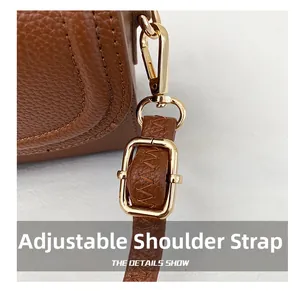 Detail of premium brown lychee leather and glossy adjustable gold buckle on the handbag