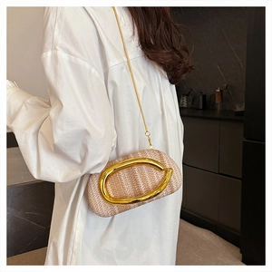 Detailed view of the woven texture and large gold oval metal hardware on the strap bag