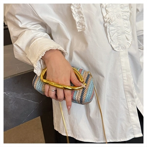 Detailed close-up of woven round box bag featuring a polished gold metal ring handle