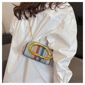 Detail of colorful woven straw box bag with large gold metal buckle and chain strap