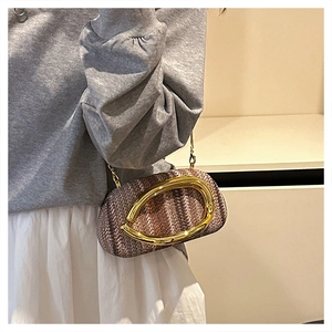 Detailed view of the woven round wrist bag with retro metal handle and textured finish