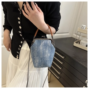 Detail of vintage blue denim shell bag with brown leather handle and metal chain strap