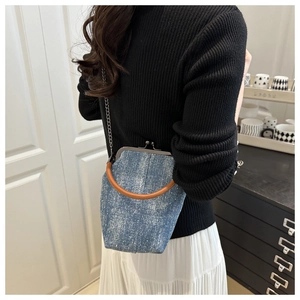 Blue denim shell bag with silver shimmer and brown leather handle on a white skirt