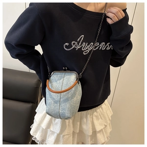 Detail of light blue denim shell bag showing retro metal kiss-lock closure and chain