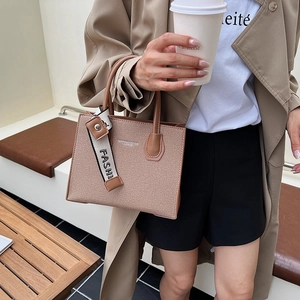 Chic brown woven tote bag with leather handles and decorative letter strap for daily commute