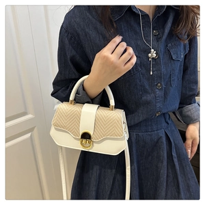 Sac à bandoulière beige chic avec rabat en paille et fermoir doré sur modèle