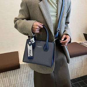 Blue denim crossbody bag with contrast stitching and woven decorative strap
