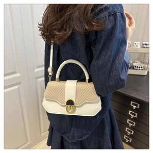 Détail d'un sac à main tressé crème avec fermoir doré sur fond de robe bleu marine
