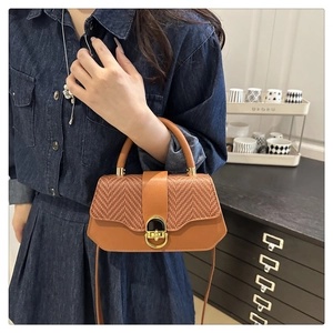 Détail du sac bandoulière en cuir tressé marron avec boucle de verrouillage dorée