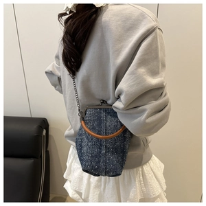 Polka dot denim shell bag with circular wooden handle and metal chain strap on model