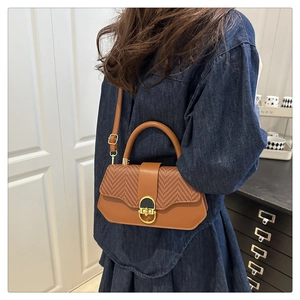 Détail d'un sac à main hexagonal en cuir tressé marron avec fermoir doré et bandoulière
