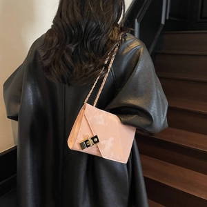 Chic pink glossy leather chain bag with gold buckle worn on a stylish black leather jacket