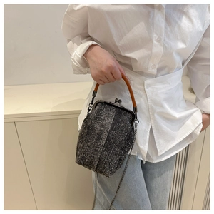 Macro view of retro dark grey tweed shell bag with vintage metal frame and handle