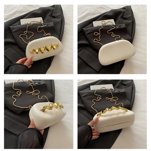 Close-up of cream box bag with unique gold wave handle and metal chain shoulder strap