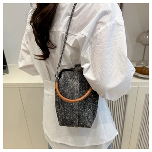 Detailed view of grey polka dot tweed handbag with vintage metal clasp and chain strap