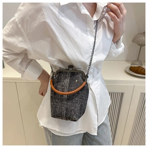 Close-up of retro tweed shell bag featuring vintage metal clasp and contrast handle