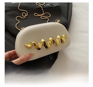 Detail showing creamy moon-shaped box bag with gold wave metal decor and snake chain