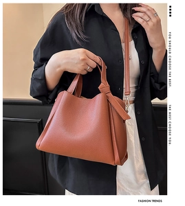 Détails du cuir grainé marron sur un sac trapèze avec des finitions dorées brillantes
