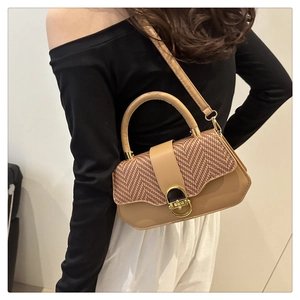 Détail d'un sac à main en cuir marron et textile tissé avec fermoir doré sur mannequin