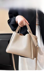 Détail du sac seau beige en cuir grainé avec poignées et bandoulière réglable