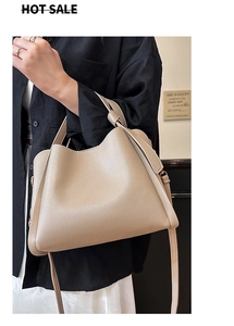 Détail d'un sac seau en cuir beige souple avec boucle métallique latérale et bandoulière
