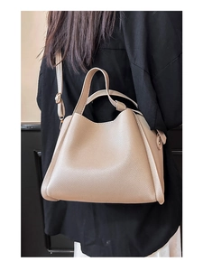 Gros plan détaillé d'un sac seau en cuir grainé beige avec garnitures dorées et bandoulière