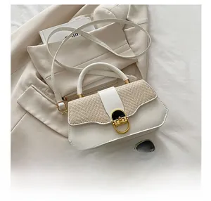 Détail du sac bandoulière en paille tressée et cuir blanc avec fermoir doré rotatif