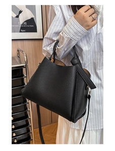 Détail du sac seau en cuir grainé noir avec poignée nouée à la main et finitions dorées