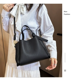 Détail d'un sac seau en cuir noir avec poignées et bandoulière réglable