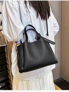 Détail du sac seau noir en cuir foulonné avec bord ondulé et poignées en anneaux