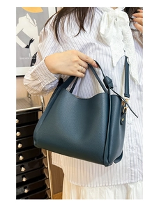 Détail d'un sac à main bleu marine en cuir grainé avec une poignée nouée élégante