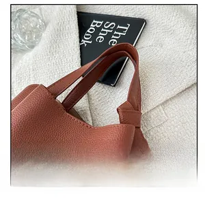 Détail de la poignée de sac à main en cuir marron avec couture sur tricot